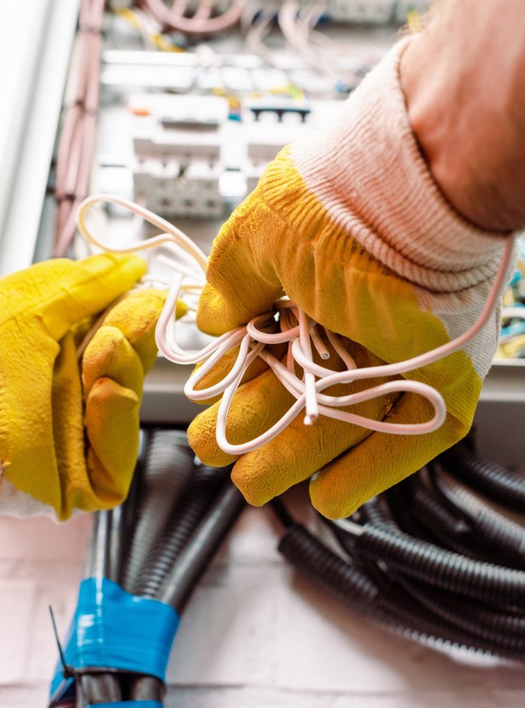 cropped-view-of-electrician-in-gloves-holding-wires-near-electrical-box